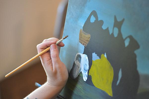 Closeup of a student's hand working on a painting