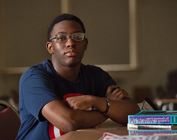 Sociology student in a classroom sitting in a desk with a few books