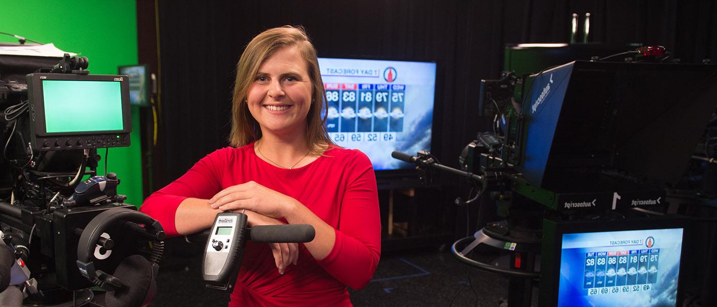 Broadcaster standing next to camera after a Meteorology broadcast in the studio